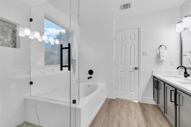 111 Woodley Rd, Leander, TX 78641 - full bathroom with double vanity, a bath, wood finished floors, and a shower with door