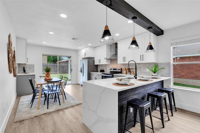 111 Woodley Rd, Leander, TX 78641 - kitchen with wall chimney range hood, stainless steel appliances, light wood-style floors, tasteful backsplash, and recessed lighting
