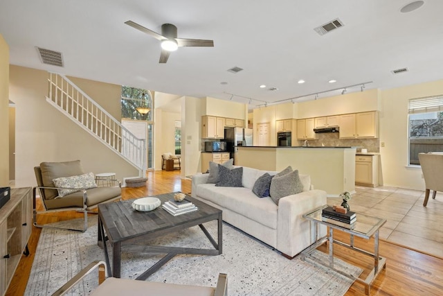 8204 Ito Cv, Austin, TX 78729 - living room with ceiling fan, stairway, light wood-type flooring, and track lighting