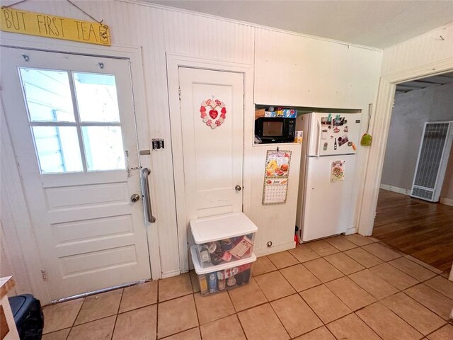 407 4th Ave, Smithville, TX 78957 - kitchen with freestanding refrigerator, a heating unit, light tile patterned flooring, and black microwave