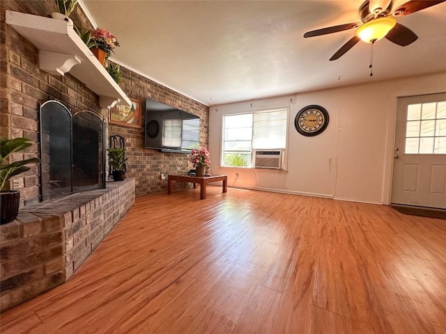 407 4th Ave, Smithville, TX 78957 - unfurnished living room featuring wood finished floors, a fireplace, brick wall, ceiling fan, and cooling unit