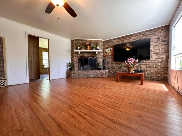 407 4th Ave, Smithville, TX 78957 - unfurnished living room featuring wood finished floors, a ceiling fan, brick wall, a fireplace, and ornamental molding
