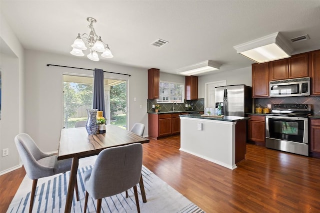 517 Castebar Dr, Round Rock, TX 78664 - kitchen with stainless steel appliances, dark countertops, a chandelier, decorative backsplash, and dark wood-type flooring