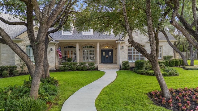 2319 Woodway Dr, Round Rock, TX 78681 - view of front facade featuring stone siding, roof with shingles, a front yard, and covered porch