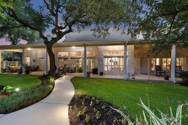 2319 Woodway Dr, Round Rock, TX 78681 - back of property at dusk with a patio area, a yard, and stone siding