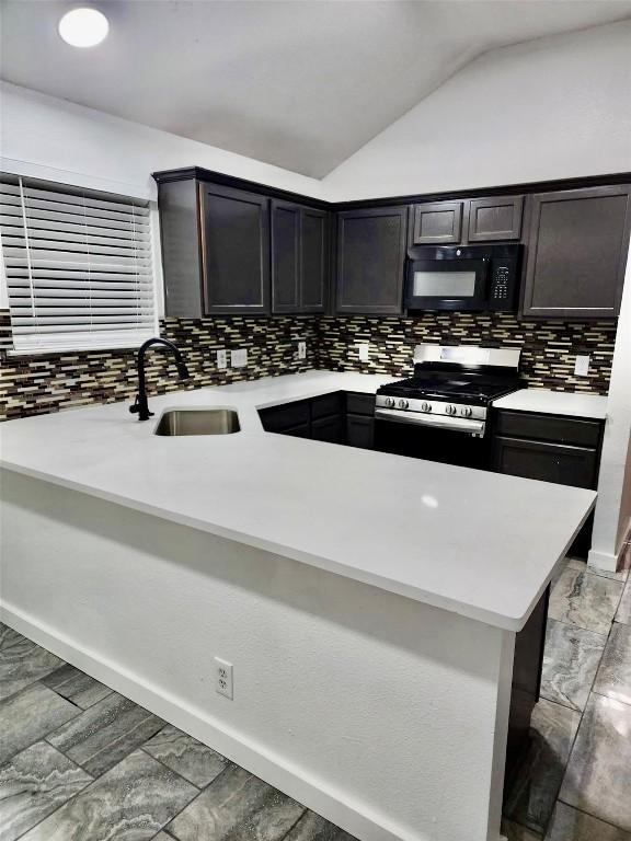 16828 Jaron Dr, Manor, TX 78653 - kitchen with black microwave, stainless steel gas stove, light countertops, tasteful backsplash, and vaulted ceiling