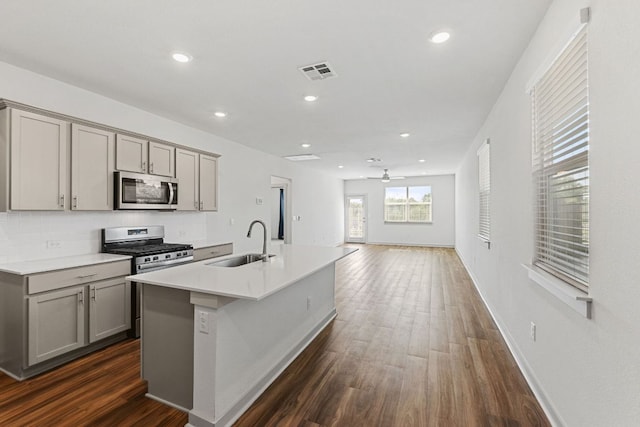 7514 Daves Landing Dr, Austin, TX 78724 - kitchen featuring appliances with stainless steel finishes, gray cabinets, a center island with sink, a ceiling fan, and recessed lighting