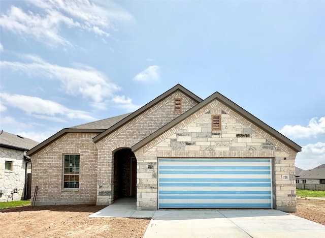 236 Du Bois Ln, Kyle, TX 78640 - french country inspired facade with driveway, a garage, and brick siding