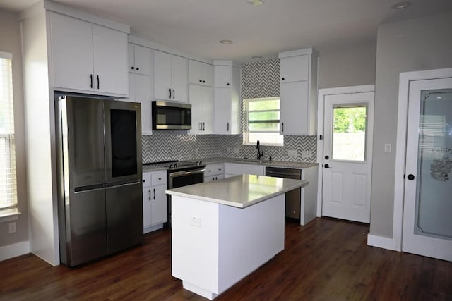 215 E 8th St, Elgin, TX 78621 - kitchen featuring appliances with stainless steel finishes, decorative backsplash, white cabinetry, light countertops, and a kitchen island