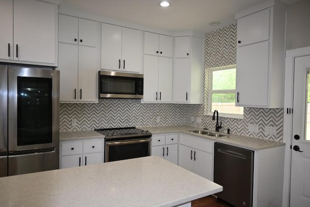 215 E 8th St, Elgin, TX 78621 - kitchen with stainless steel appliances, white cabinets, tasteful backsplash, light stone counters, and recessed lighting