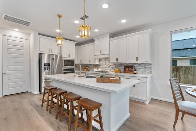 2437 Burberry Ln, Leander, TX 78641 - kitchen featuring stainless steel appliances, light wood-type flooring, light countertops, backsplash, and recessed lighting