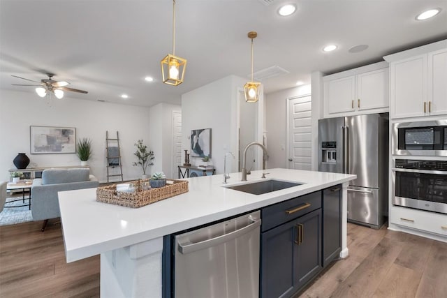 2437 Burberry Ln, Leander, TX 78641 - kitchen featuring appliances with stainless steel finishes, white cabinets, an island with sink, light countertops, and recessed lighting
