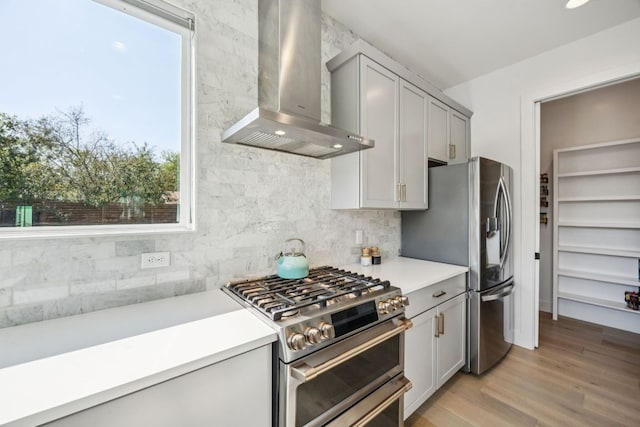 5703 Taunton Dr, Austin, TX 78723 - kitchen featuring wall chimney exhaust hood, appliances with stainless steel finishes, backsplash, light countertops, and light wood finished floors