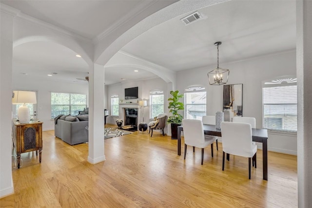 5511 Oakwood Cv Unit B, Austin, TX 78731 - dining space featuring a fireplace, ceiling fan, a chandelier, arched walkways, and light wood-style flooring