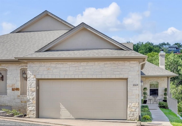 5511 Oakwood Cv Unit B, Austin, TX 78731 - french country home featuring stone siding, roof with shingles, a garage, and a chimney