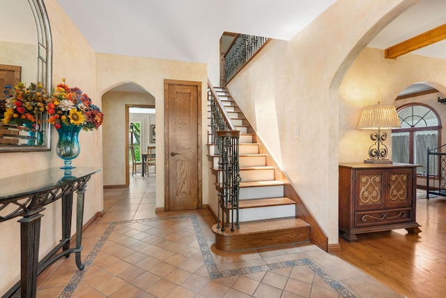 11923 Brookwood Cir, Austin, TX 78750 - entryway featuring arched walkways, inlaid floor details, stairway, beamed ceiling, and tile patterned floors