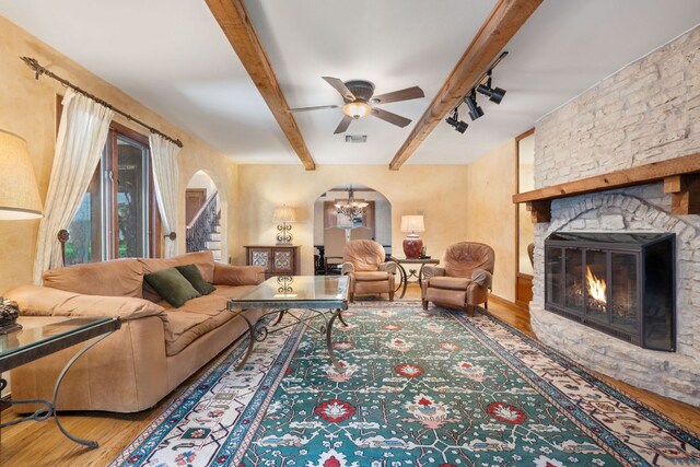 11923 Brookwood Cir, Austin, TX 78750 - living area featuring wood finished floors, arched walkways, a stone fireplace, beam ceiling, and a ceiling fan
