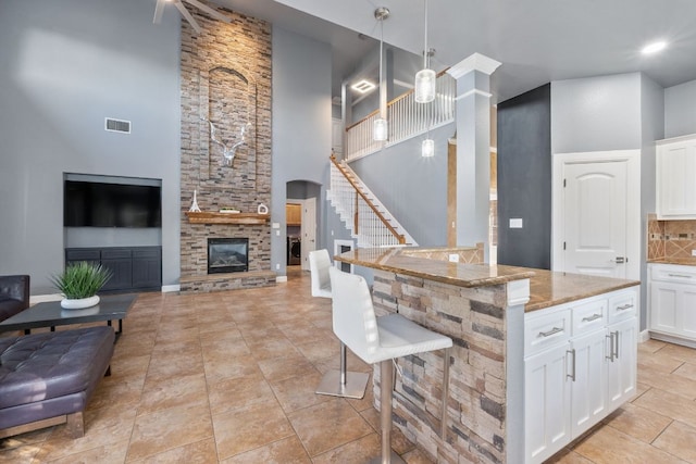 1000 Williams Way, Cedar Park, TX 78613 - kitchen featuring a towering ceiling, a kitchen bar, light stone counters, hanging light fixtures, and open floor plan
