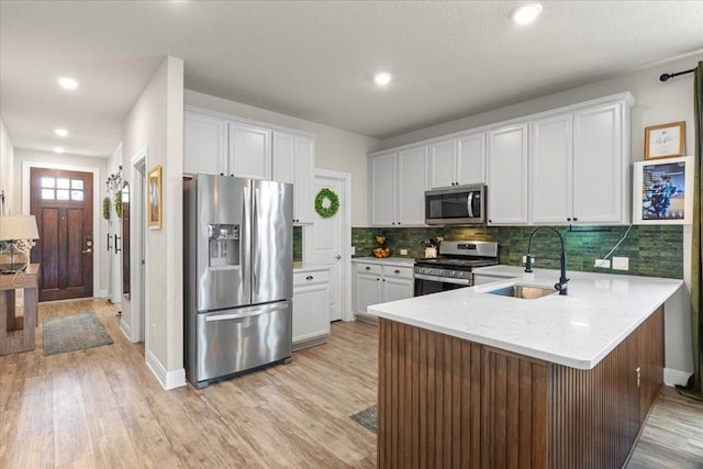 496 Sawtooth Mountain Way, Dripping Springs, TX 78620 - kitchen with appliances with stainless steel finishes, light wood-style floors, a peninsula, tasteful backsplash, and recessed lighting