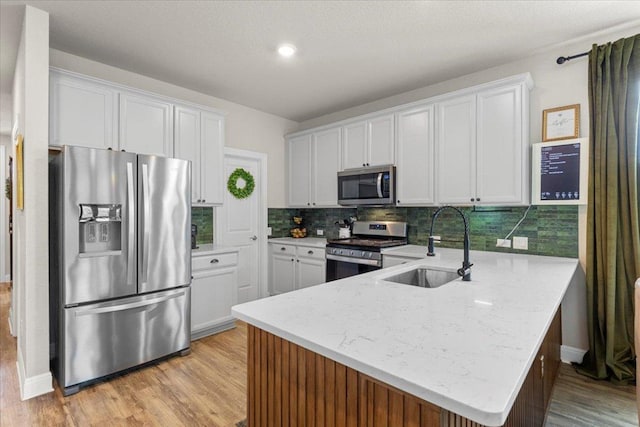 496 Sawtooth Mountain Way, Dripping Springs, TX 78620 - kitchen featuring stainless steel appliances, a peninsula, light wood-type flooring, backsplash, and white cabinets