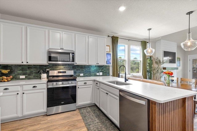 496 Sawtooth Mountain Way, Dripping Springs, TX 78620 - kitchen featuring stainless steel appliances, a peninsula, tasteful backsplash, light countertops, and white cabinetry