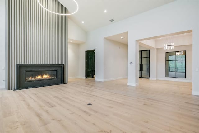 5217 S Scout Island Cir, Austin, TX 78731 - unfurnished living room featuring wood finished floors, a chandelier, high vaulted ceiling, a glass covered fireplace, and recessed lighting