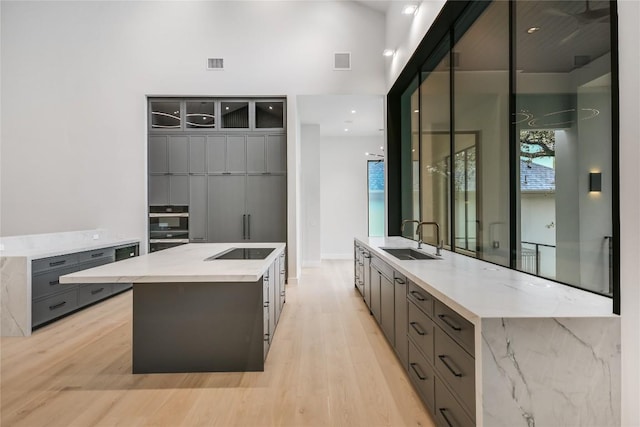 5217 S Scout Island Cir, Austin, TX 78731 - kitchen with gray cabinetry, a large island, light wood-style floors, black electric stovetop, and modern cabinets