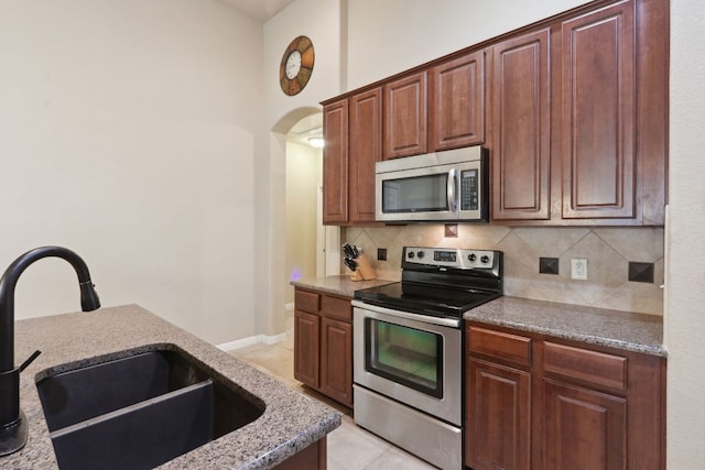 7233 Menchaca Rd Unit 22, Austin, TX 78745 - kitchen with appliances with stainless steel finishes, decorative backsplash, light stone countertops, and light tile patterned floors
