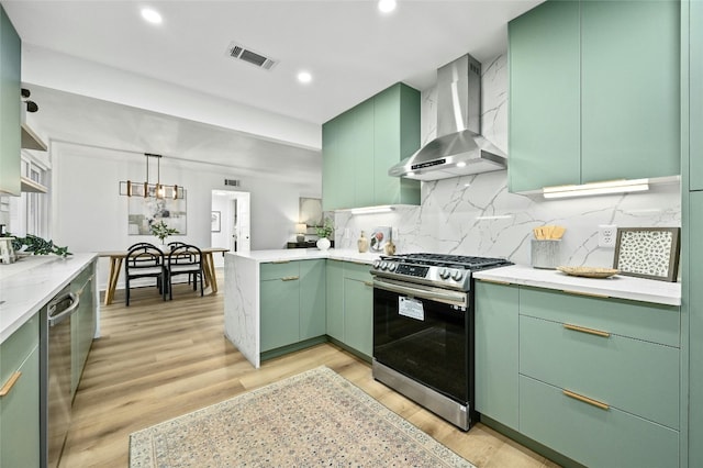 2114 Vanderbilt Ln, Austin, TX 78723 - kitchen featuring appliances with stainless steel finishes, wall chimney range hood, green cabinetry, light wood-style floors, and backsplash