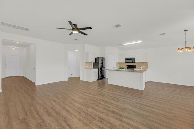 608 Silver Wing Dr, Austin, TX 78725 - unfurnished living room with ceiling fan, a chandelier, and wood finished floors