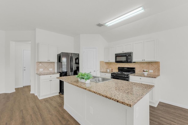 608 Silver Wing Dr, Austin, TX 78725 - kitchen featuring black appliances, backsplash, light wood-style flooring, white cabinetry, and a kitchen island with sink