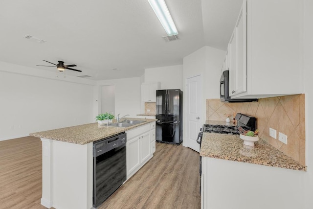 608 Silver Wing Dr, Austin, TX 78725 - kitchen featuring black appliances, light wood-type flooring, white cabinetry, and backsplash