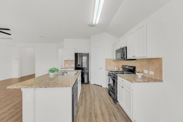 608 Silver Wing Dr, Austin, TX 78725 - kitchen featuring black appliances, light wood-style floors, white cabinets, and backsplash