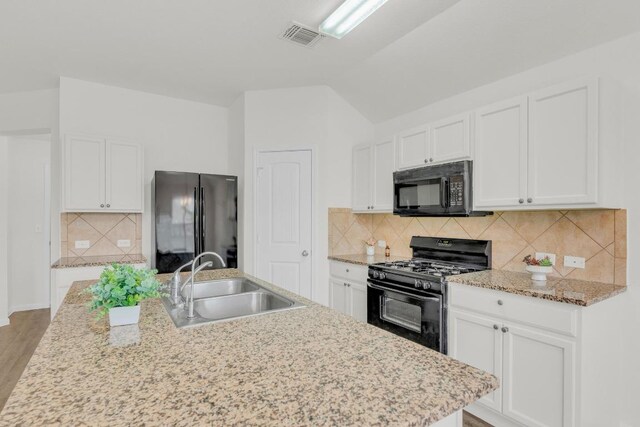 608 Silver Wing Dr, Austin, TX 78725 - kitchen featuring black appliances, white cabinets, decorative backsplash, and vaulted ceiling