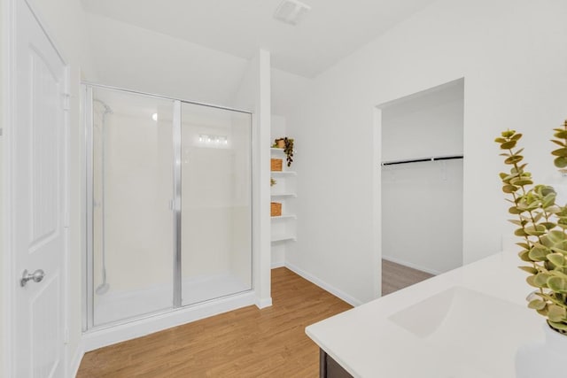 608 Silver Wing Dr, Austin, TX 78725 - full bathroom featuring a stall shower, wood finished floors, vanity, and a walk in closet