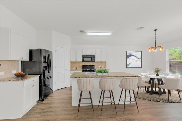 608 Silver Wing Dr, Austin, TX 78725 - kitchen featuring black appliances, light wood-style floors, a chandelier, and white cabinetry