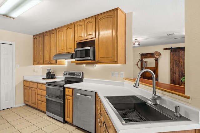 11551 Fm 32, Fischer, TX 78623 - kitchen with appliances with stainless steel finishes, light countertops, light tile patterned floors, under cabinet range hood, and brown cabinetry