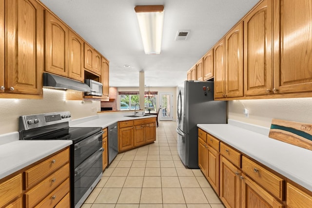 11551 Fm 32, Fischer, TX 78623 - kitchen with stainless steel appliances, under cabinet range hood, light tile patterned floors, brown cabinetry, and light countertops