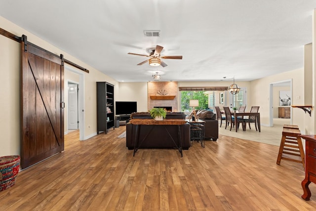 11551 Fm 32, Fischer, TX 78623 - living room with light wood-type flooring, ceiling fan, a barn door, and a brick fireplace