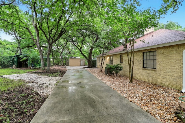 1203 Arbor Ln, Marble Falls, TX 78654 - view of side of home featuring a storage shed, brick siding, a shingled roof, a chimney, and driveway