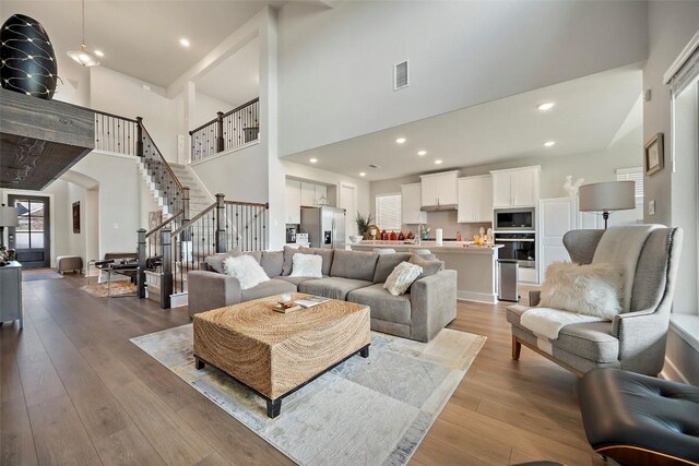 1113 Spring Gulch Ln, Georgetown, TX 78628 - living area featuring a high ceiling, stairway, wood-type flooring, arched walkways, and recessed lighting