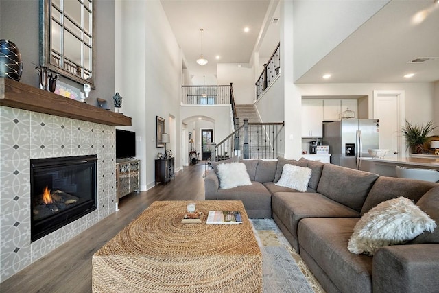 1113 Spring Gulch Ln, Georgetown, TX 78628 - living area featuring wood finished floors, arched walkways, stairs, a towering ceiling, and a fireplace