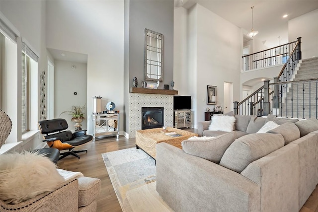 1113 Spring Gulch Ln, Georgetown, TX 78628 - living room featuring a high ceiling, a tiled fireplace, wood finished floors, and stairway
