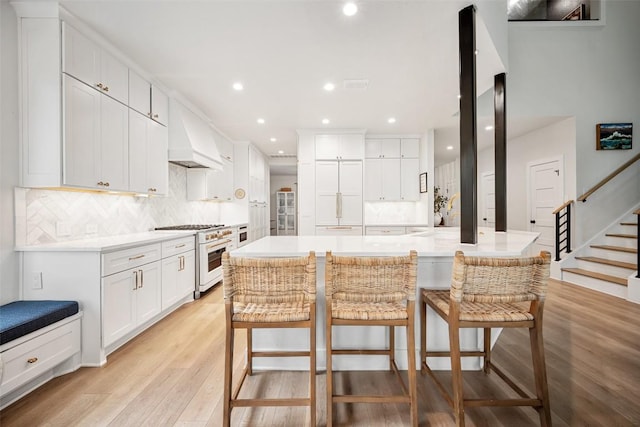 7308 Black Mountain Dr, Austin, TX 78736 - kitchen with high end white range, a kitchen breakfast bar, recessed lighting, light wood finished floors, and premium range hood