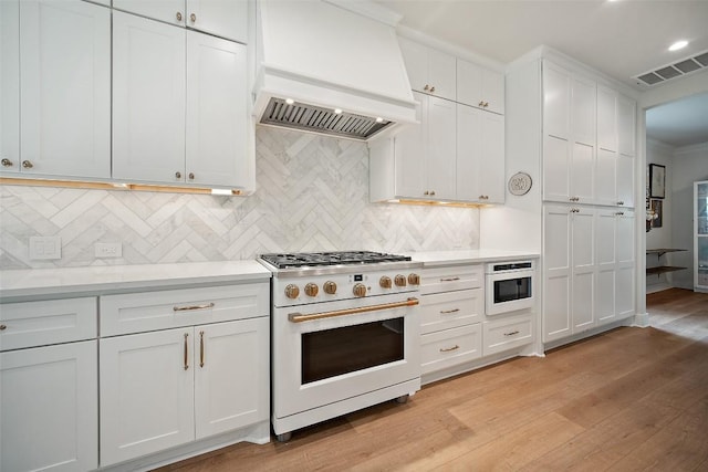 7308 Black Mountain Dr, Austin, TX 78736 - kitchen with high end white range oven, wall chimney exhaust hood, light wood finished floors, light countertops, and tasteful backsplash