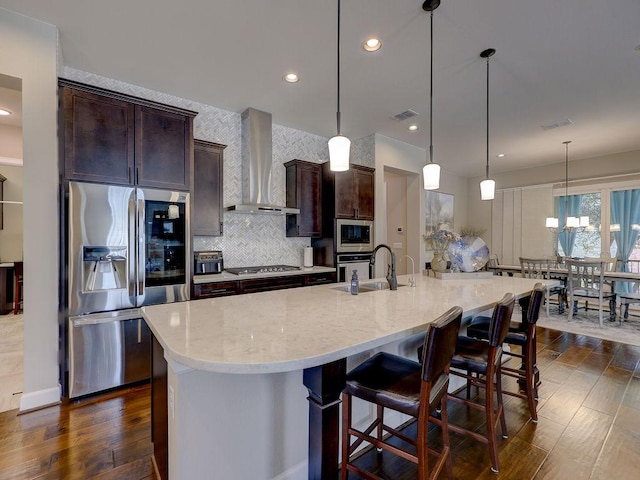 217 Skipping Cedar St, San Marcos, TX 78666 - kitchen featuring stainless steel appliances, wall chimney range hood, dark wood-type flooring, backsplash, and dark brown cabinetry