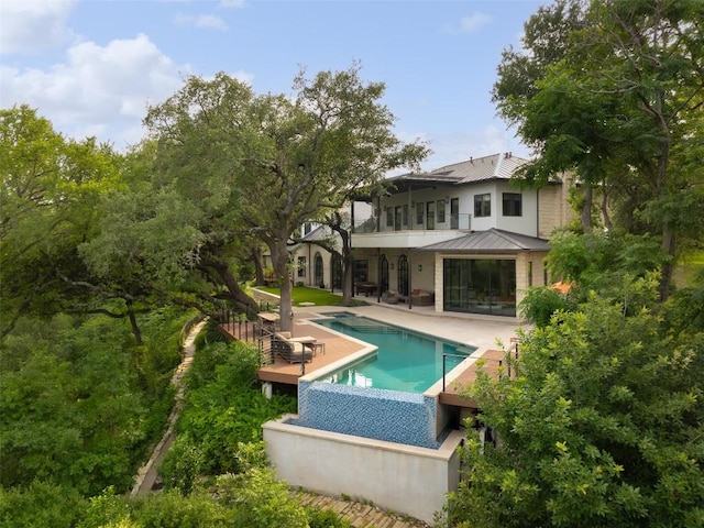 5301 Maryanna Dr, Austin, TX 78746 - rear view of property featuring a patio area, an outdoor pool, a metal roof, a standing seam roof, and a balcony