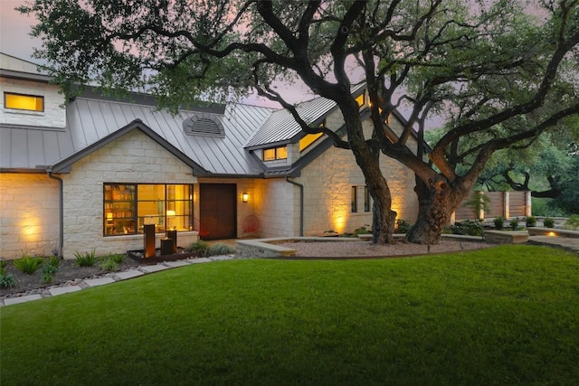 5301 Maryanna Dr, Austin, TX 78746 - rear view of house featuring stone siding, a standing seam roof, a yard, and a metal roof