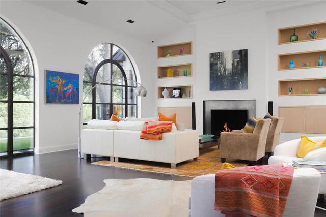 5301 Maryanna Dr, Austin, TX 78746 - living area with built in features, healthy amount of natural light, wood finished floors, a lit fireplace, and ornamental molding