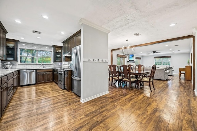 2802 Brandy Ln, Georgetown, TX 78628 - kitchen featuring appliances with stainless steel finishes, dark wood finished floors, dark brown cabinetry, ornamental molding, and recessed lighting